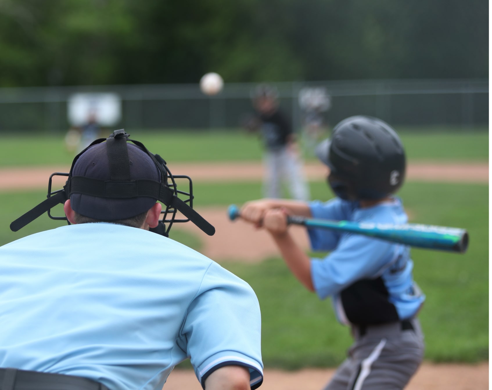 An umpire behind a young baseball player readying for a pitch